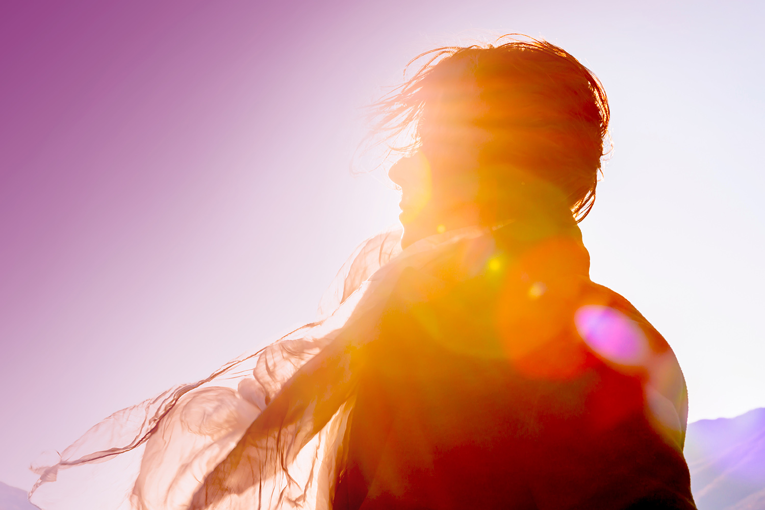 Das Bild zeigt eine Frau, die im Gegenlicht der Sonne steht
