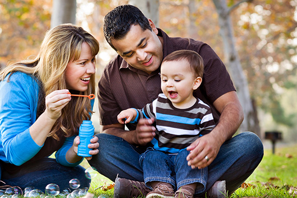 Mutter, Vater und Kind spielen mit Seifenblasen